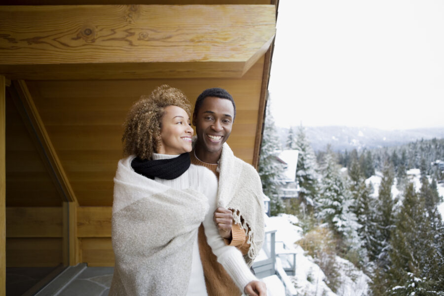 Couple wearing a blanket on deco of winter cabin