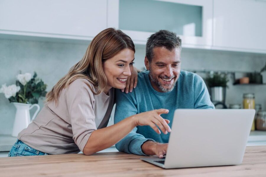 Happy couple using laptop in the kitchen