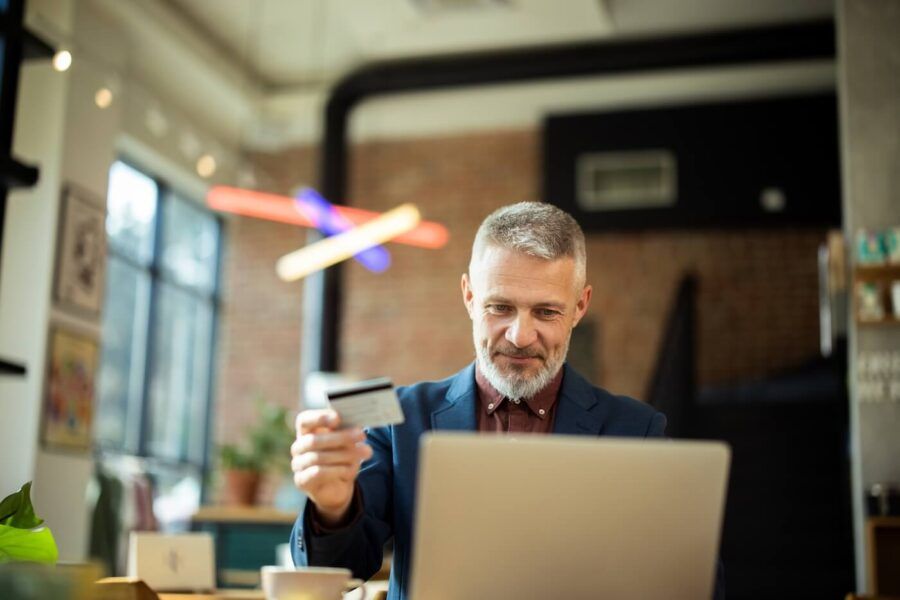 Mature businessman making online payment with credit card in the cafe