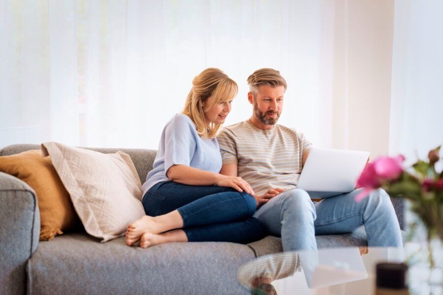 Mature couple sitting on a sofa and using a laptop together