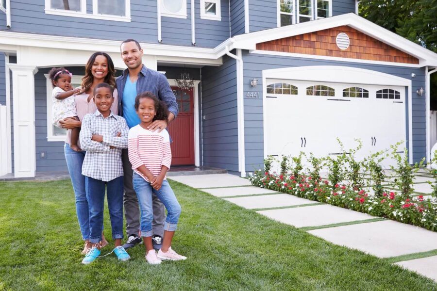 Happy family of five posing for a photo in front of their new house