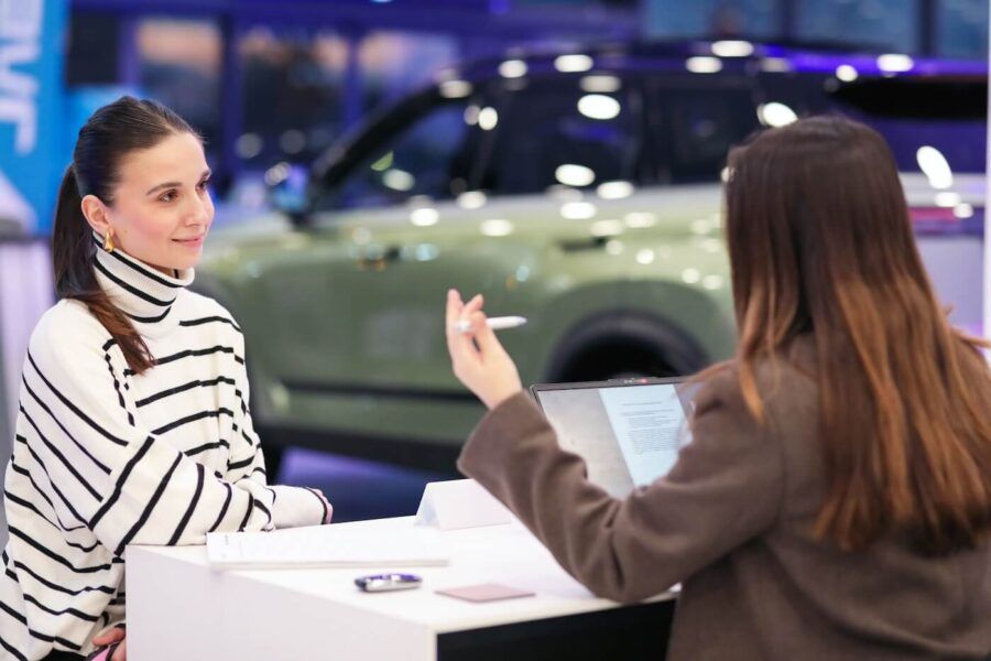 Smiling woman discussing auto loan terms with a female dealership agent
