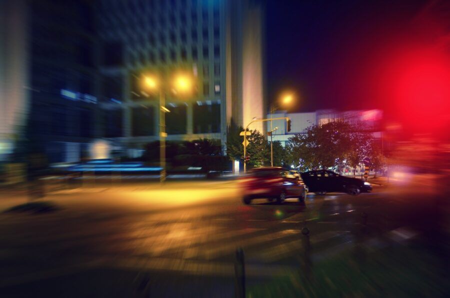 A blurry shot of two cars about to collide on a city street at night.