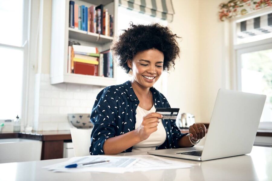 Smiling woman using her credit card online at home