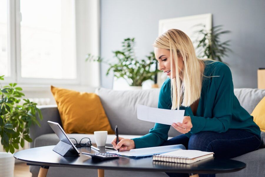 Smiling woman reviewing 401k documents while at sitting on sofa at home.