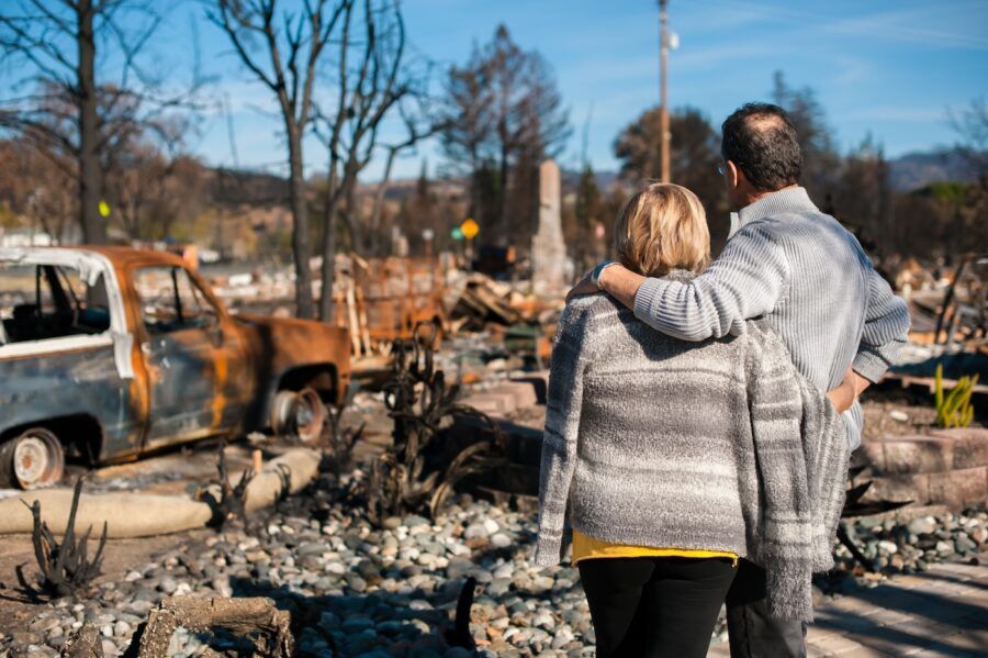 A couple checking burned and ruined house and yard after fire.