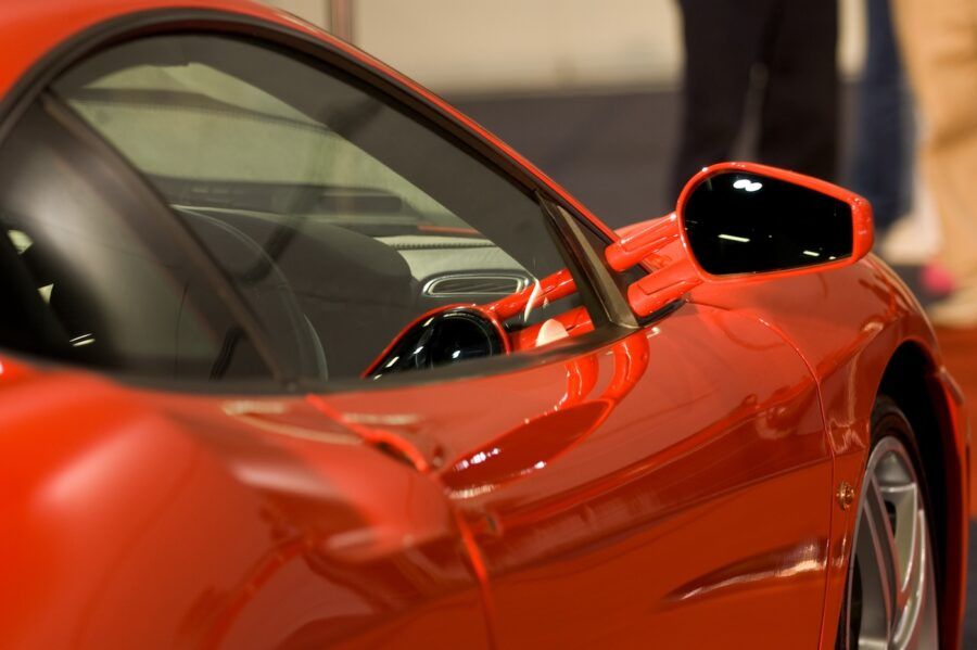 Close shot of right side mirror of exotic shiny red sports car.