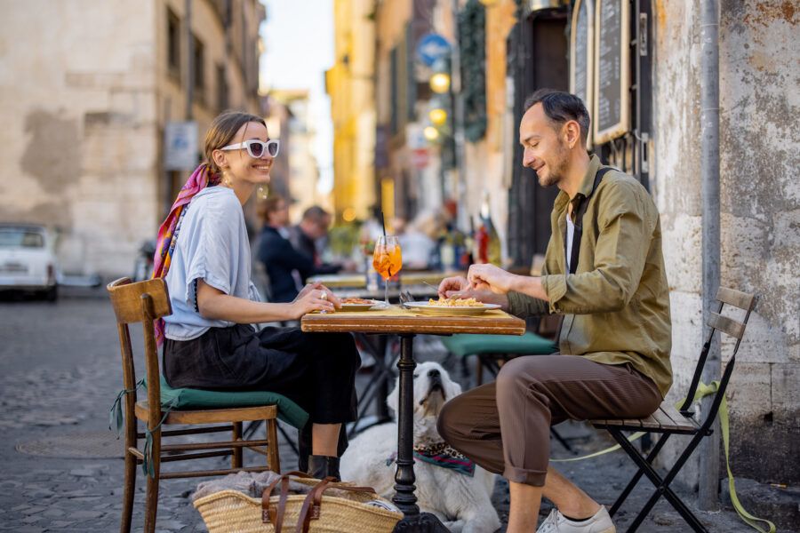 Man and woman eating italian pasta and drinking wine at restaurant on the street in Rome.