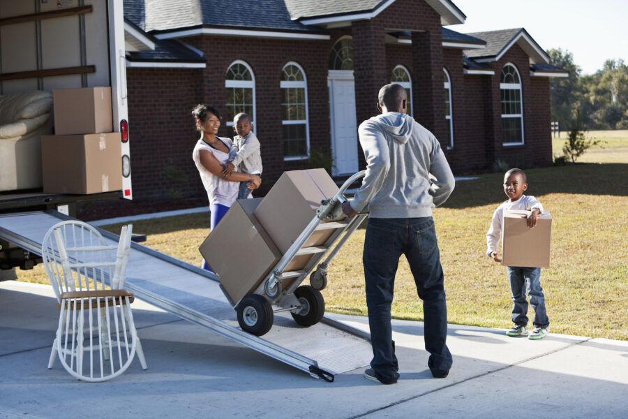 A family moving house. Main focus on man and little boy carrying box.