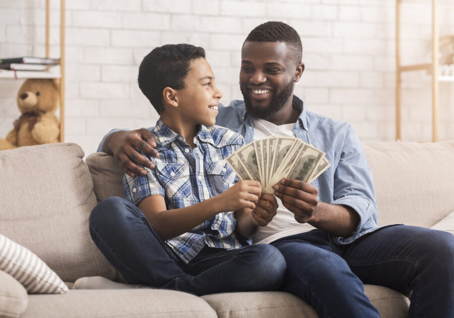 Father helping son count money to open a savings account.
