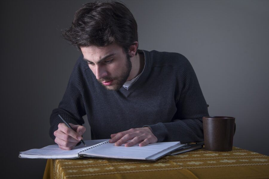 Young man sitting at a table writing a financial aid appeal letter.