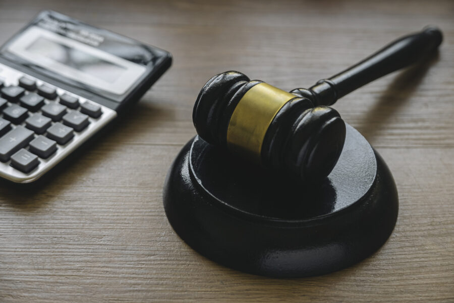 A gavel and a calculator sitting on a desk.