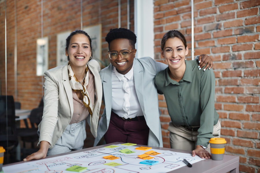 A group of 3 smiling female entrepreneurs in an office