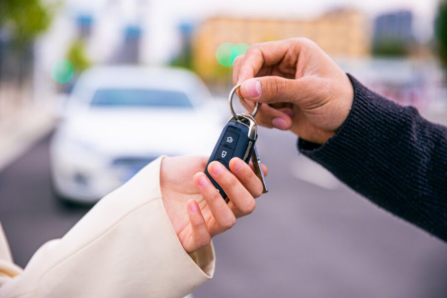 A person trading in their car and receiving new keys. A pair of car keys being handed from one hand to another.
