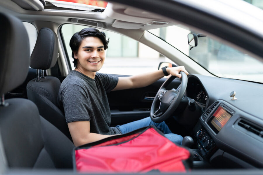 Smiling young delivery man driving car
