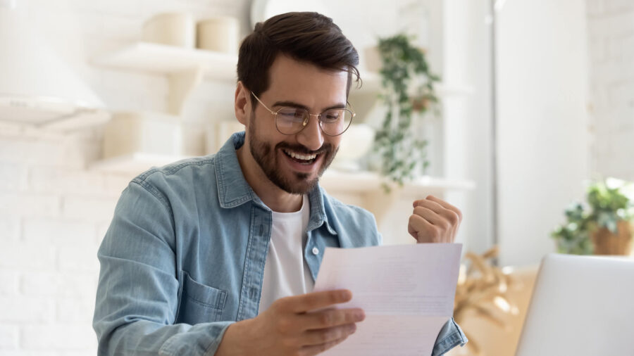 Happy man excitedly pumping his fist while looking at paper.