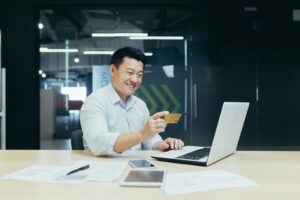 Happy man using credit card, learning about cash advance fees