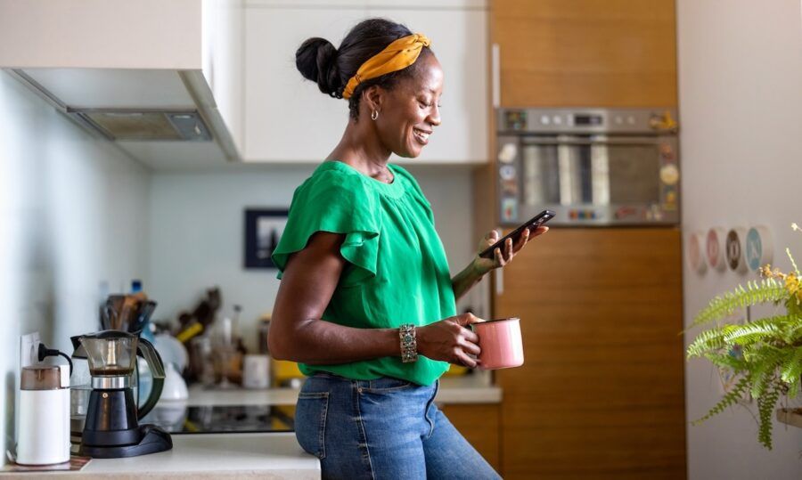 Mature woman using smartphone in the kitchen at home