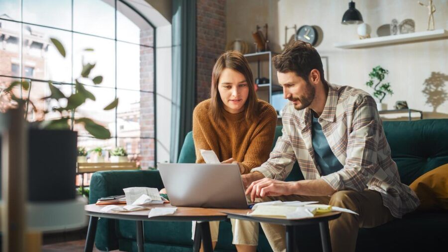 Young couple using laptop at home to organize their finances