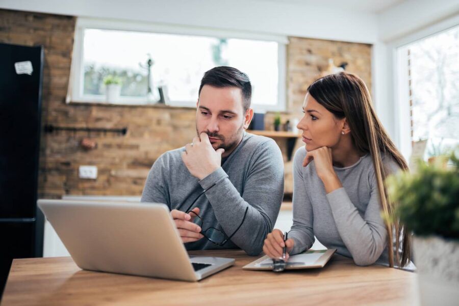 Concerned couple making a tough financial decision while using a laptop at home