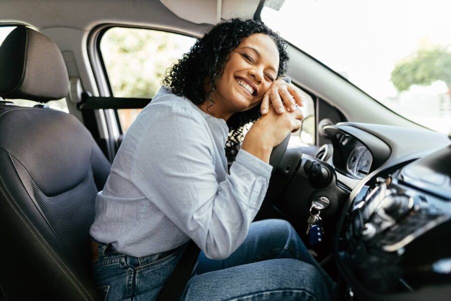 Smiling woman leaning against the car wheel