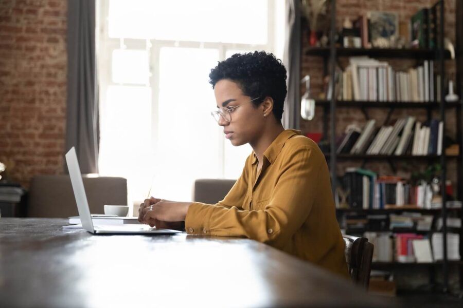 Focused young woman using her laptop at home