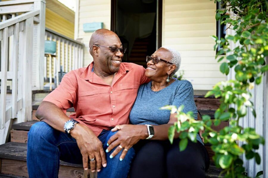 Happy senior couple sitting on the porch of their house, embracing each other