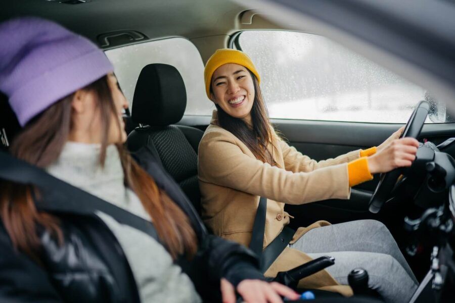 Two female friends traveling by car in winter