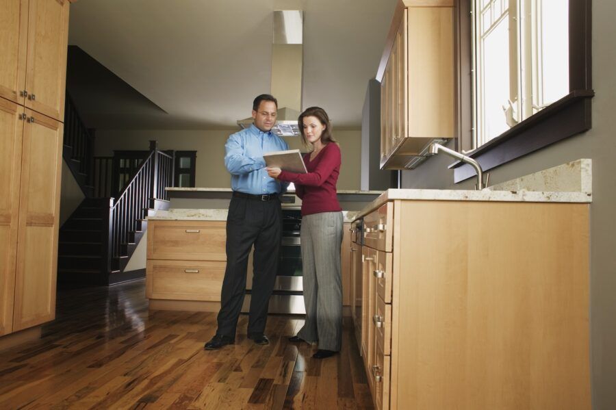 Man and woman standing in kitchen reading document