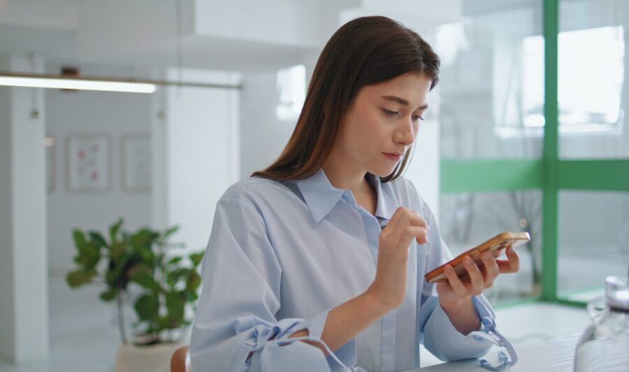 Focused young woman checking her smartphone on the office