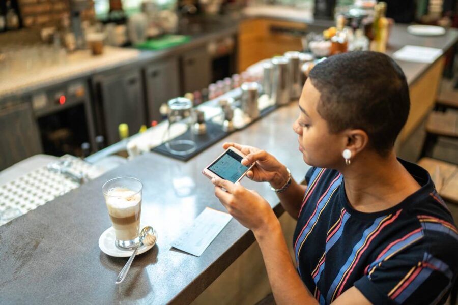 Young woman making a photo of a check while enjoying her latte in the cafe