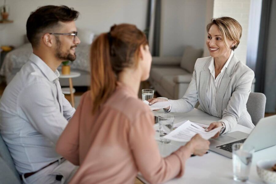 Happy couple receiving documents from a female lender in her office