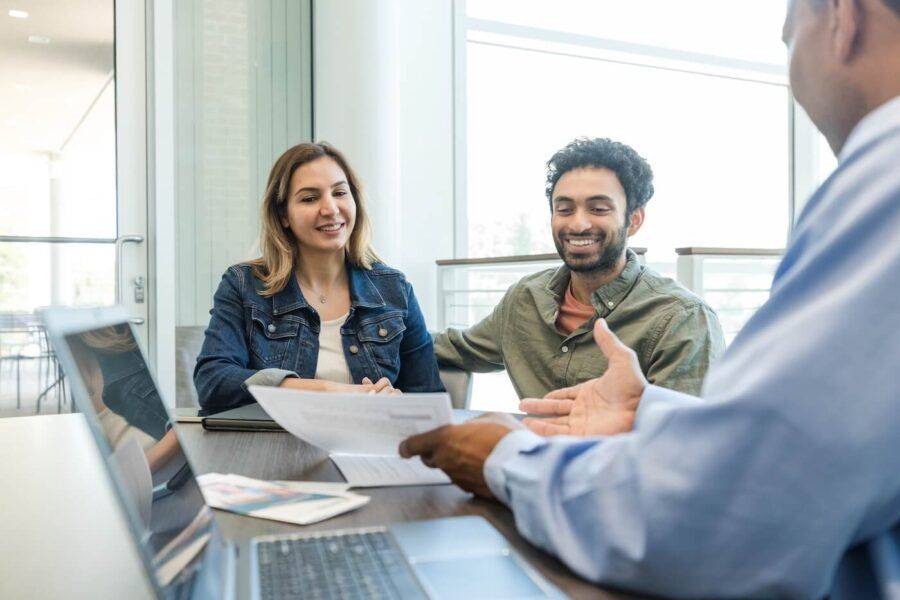 Happy couple sitting with a credit counselor at his office, reviewing the printed documents