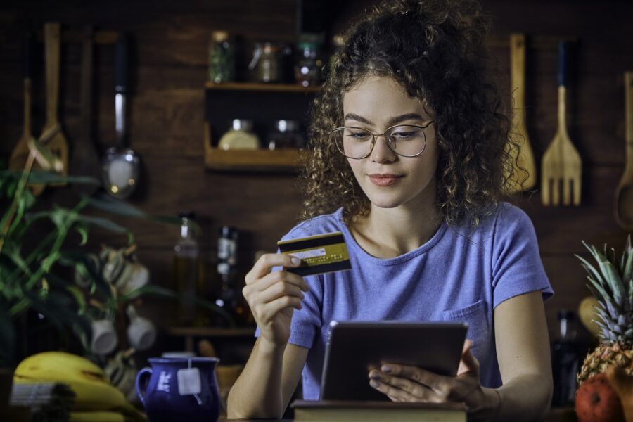 A woman shopping online using smart phone in a low key rustic kitchen