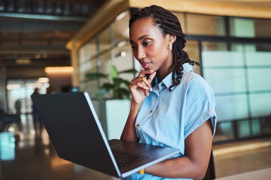 Pensive businesswoman holding an open laptop while standing in the office
