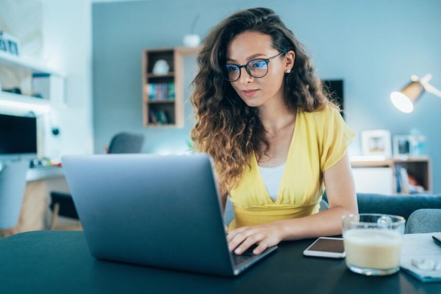 Young woman in glasses making wire transfer online at home