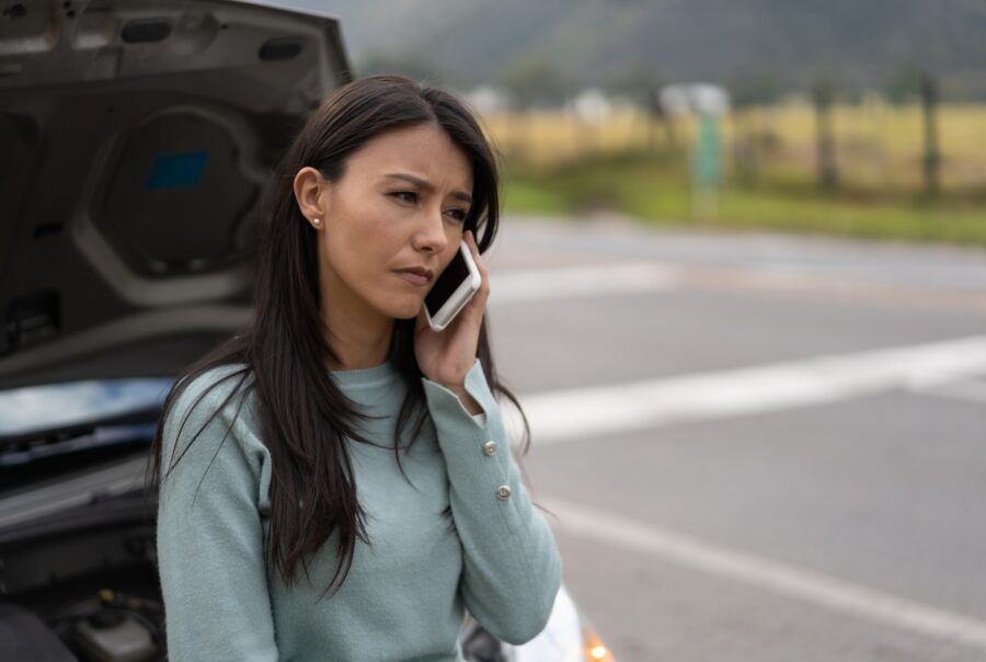 A woman calling her insurance for roadside assistance.