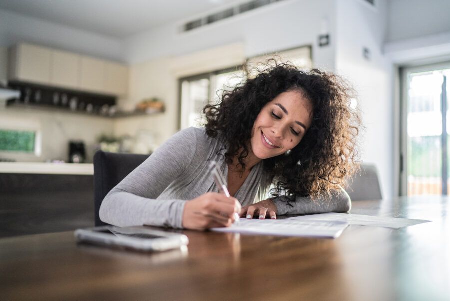 Woman writing down goals for high yield savings account