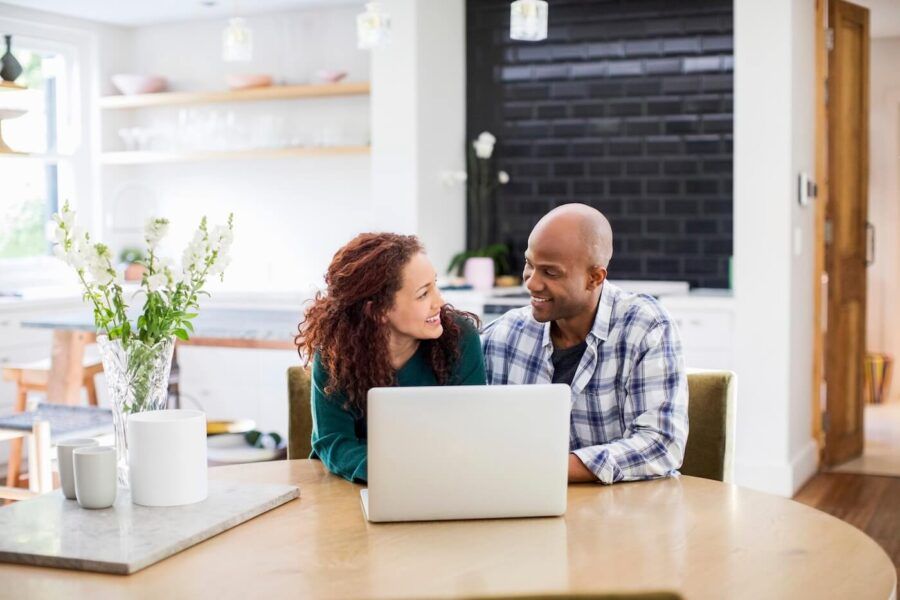 Happy couple using a laptop in the modern kitchen