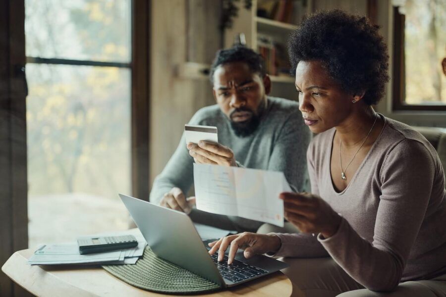 Concerned couple using a credit card and a laptop to pay bills at home
