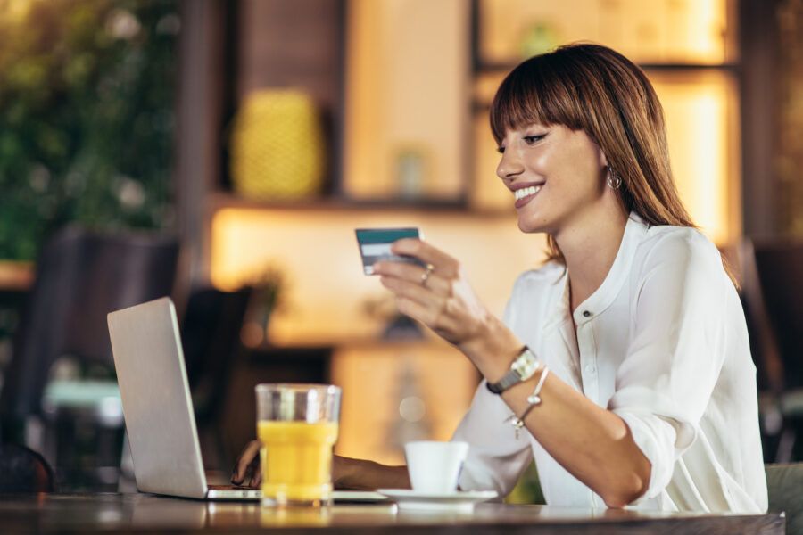 Young woman sitting in cafe and using secured credit card for online shopping
