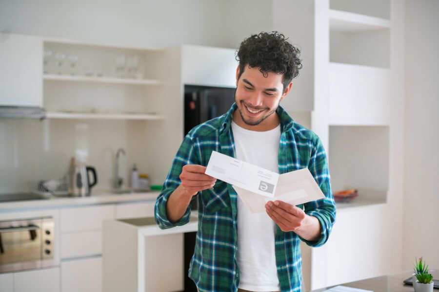 Happy man at home reading bank statement