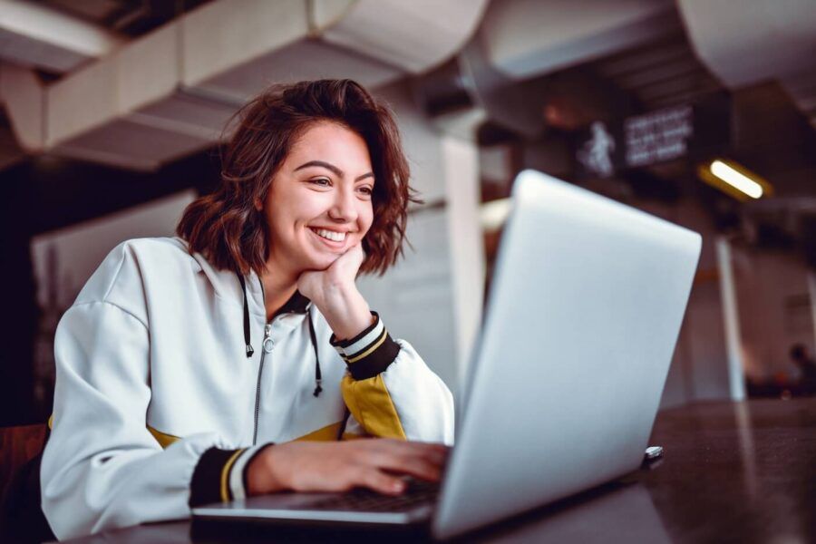 Smiling young woman in a sports outfit using her laptop.