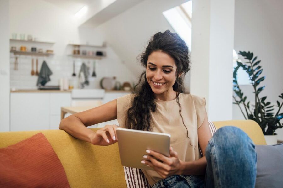 Smiling woman using her tablet while sitting comfortably on a couch