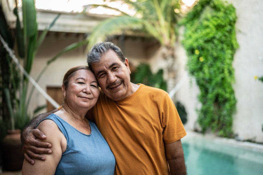 Portrait of a happy mature couple embracing by the pool in their beautiful backyard.