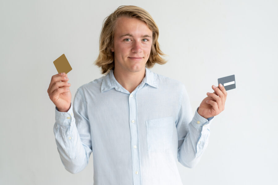 Smiling blonde guy holding two credit cards.