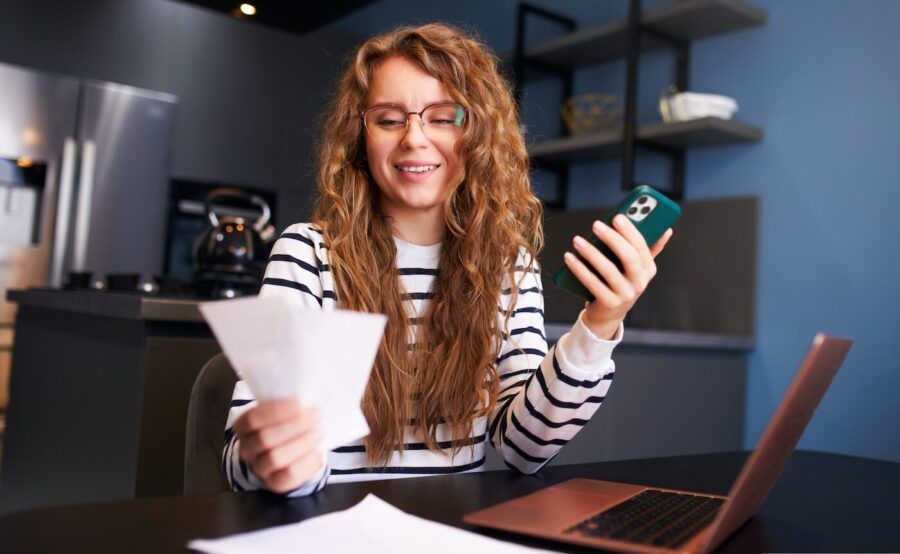 Smiling young woman using mobile app to track her expenses
