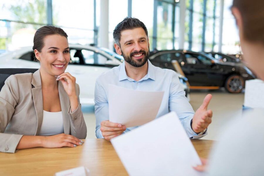 A couple discussing a cat title transfer with a dealership agent
