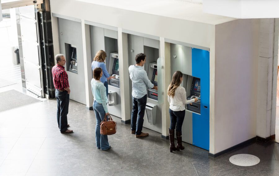 Group of people withdrawing cash at a group of ATMs