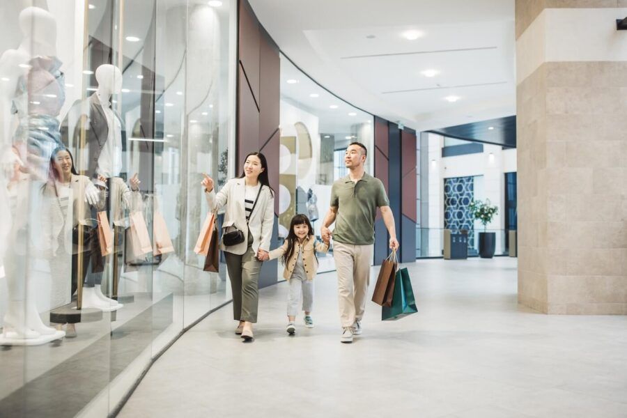 Happy family with a toddler girl enjoying shopping in a mall